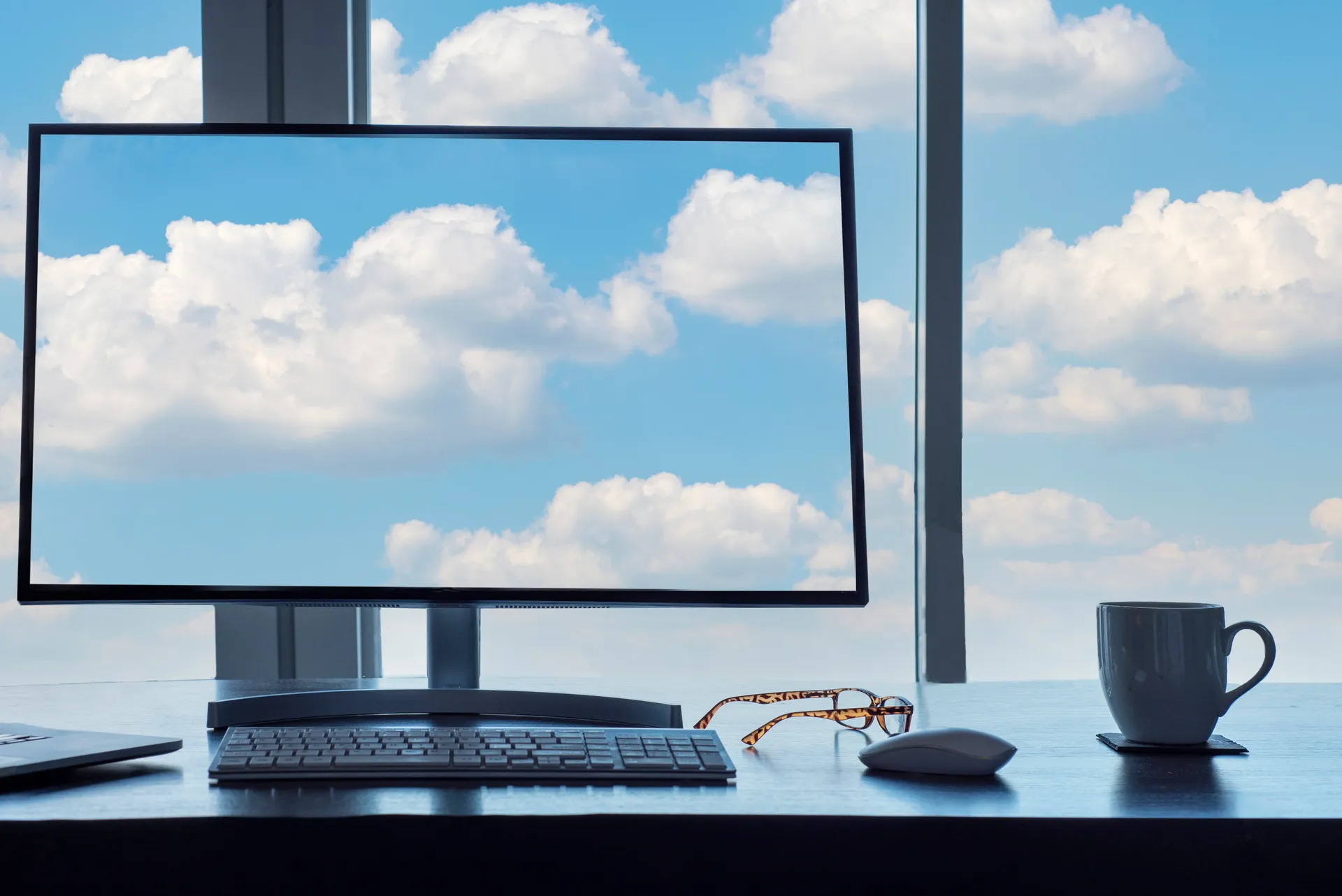 A computer keyboard on a desk with a cloud computing graphic overlaid